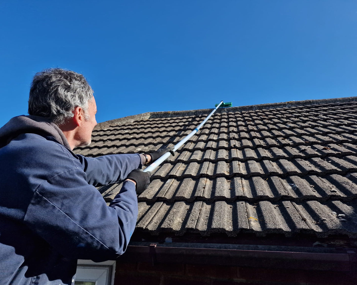 removing moss from a pitched roof with our telescopic broom