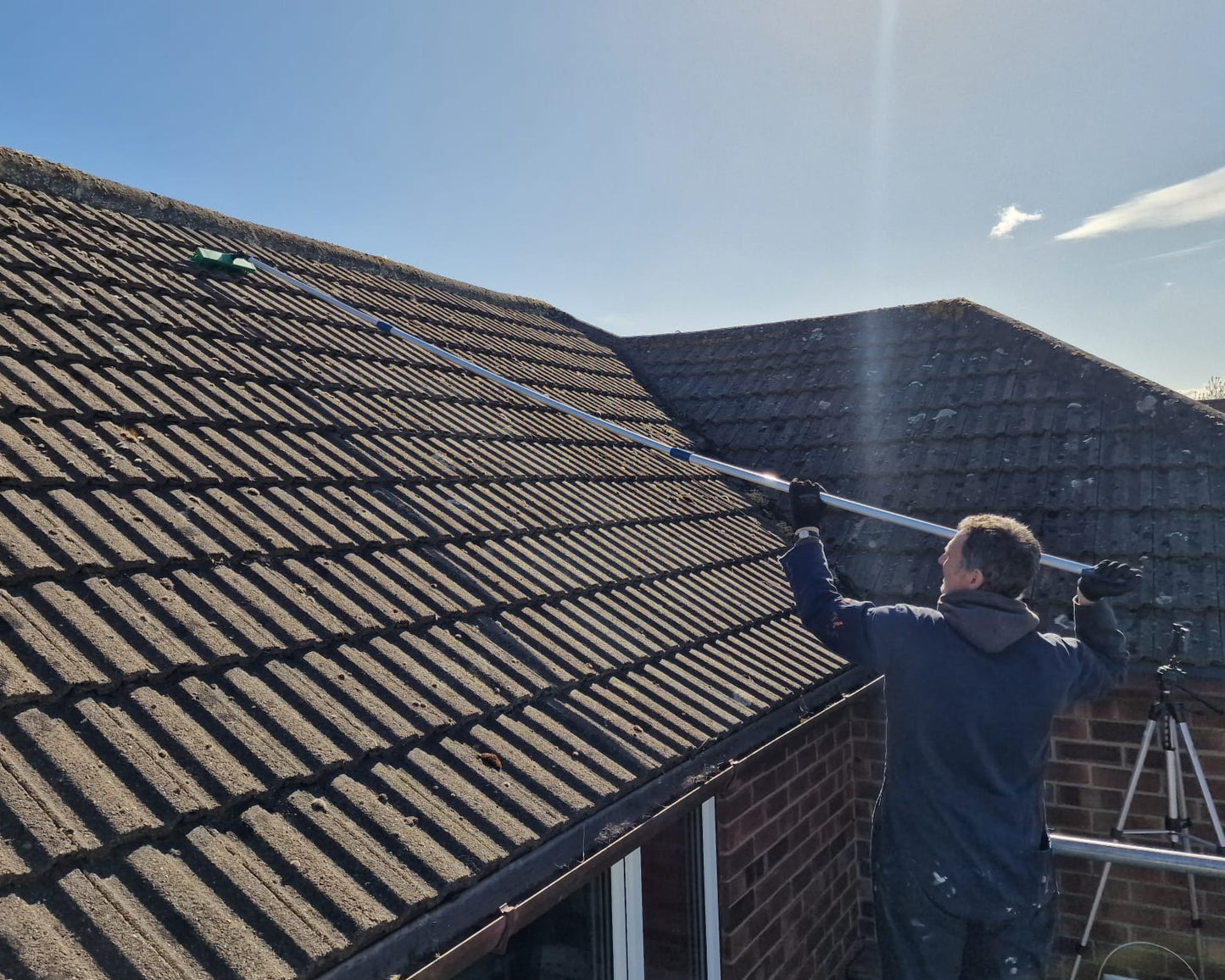 sweeping moss from a tiled roof with our telescopic broom